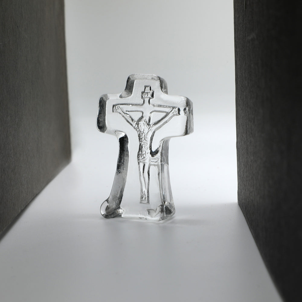 crystal crucifix on a reflective surface with a neutral background
