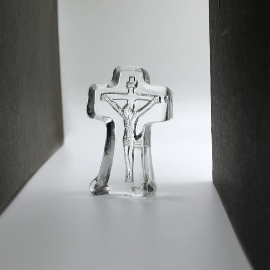 crystal crucifix on a reflective surface with a neutral background