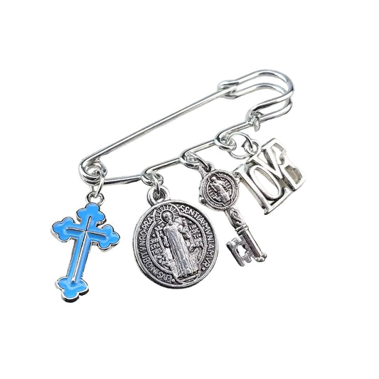 Silver brooch with Blue charms including a cross, key, and circular design on a textured surface.